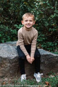 Young boy posing sitting on rock with Ron Schroll Photography at Bridge to Antiquity in Davidson, NC.